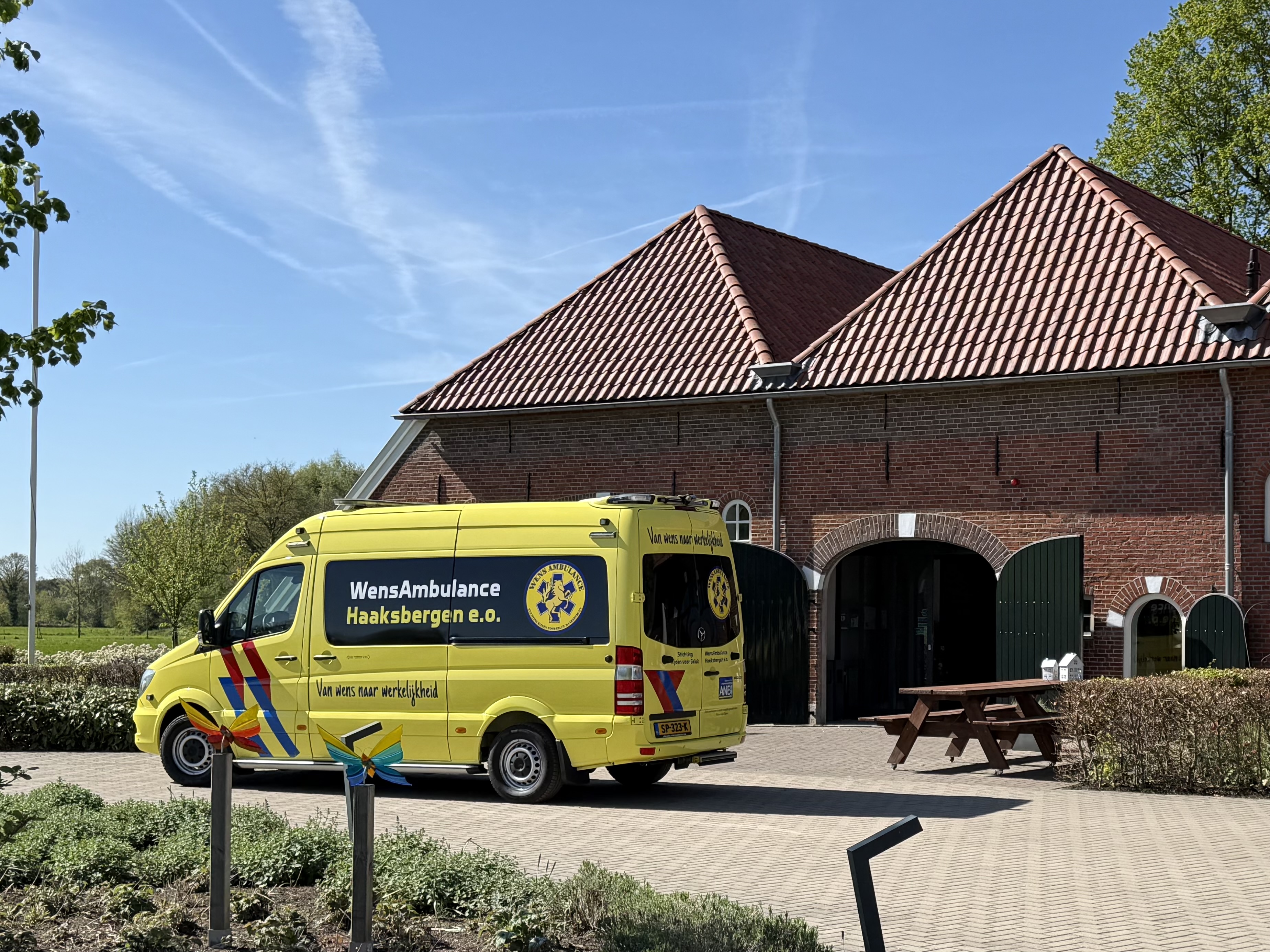 De gele WensAmbulance van Stichting Rijden voor Geluk geparkeerd voor een Twentse boerderij
